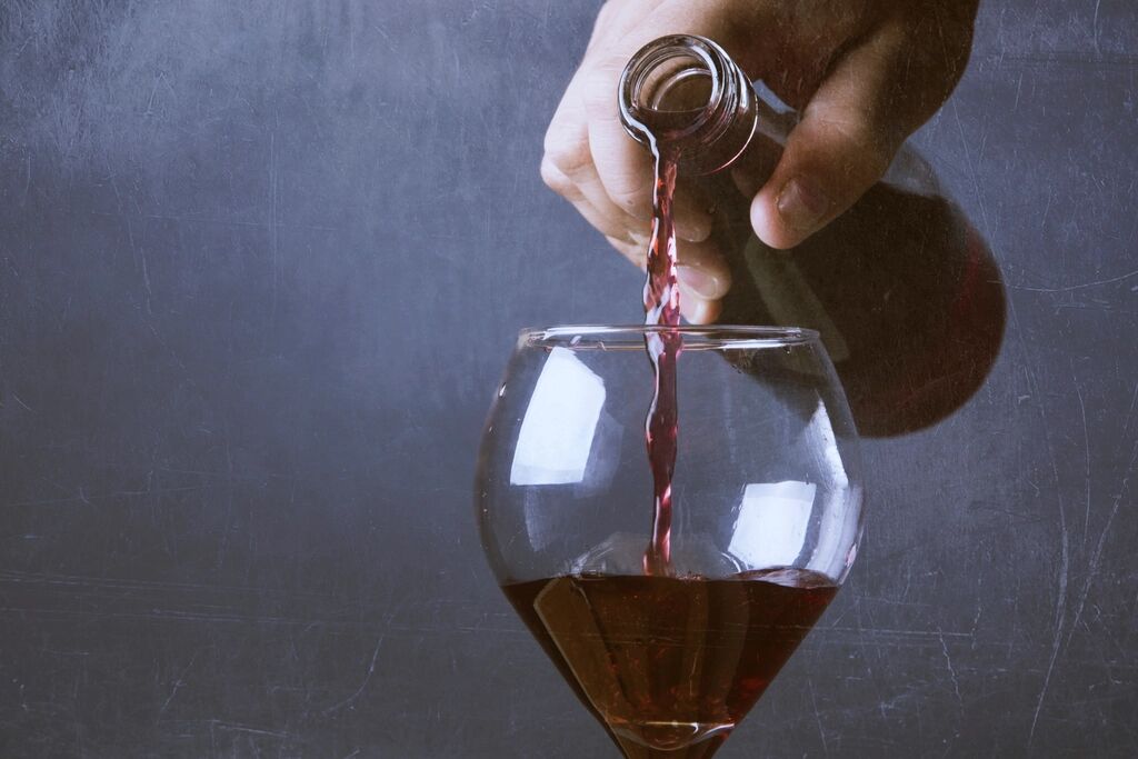 Red wine being poured into a glass in a cellar